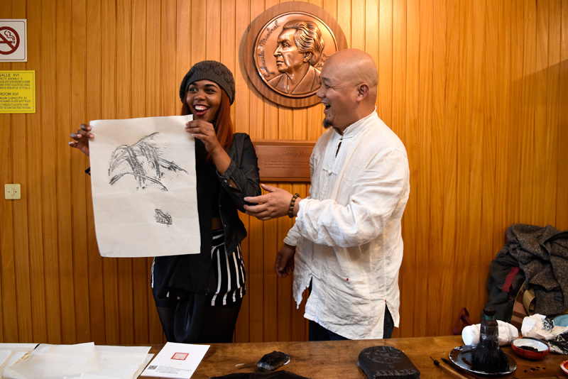10月20日，联合国教科文组织工作人员（左）在法国巴黎展示其亲手拓印的作品。